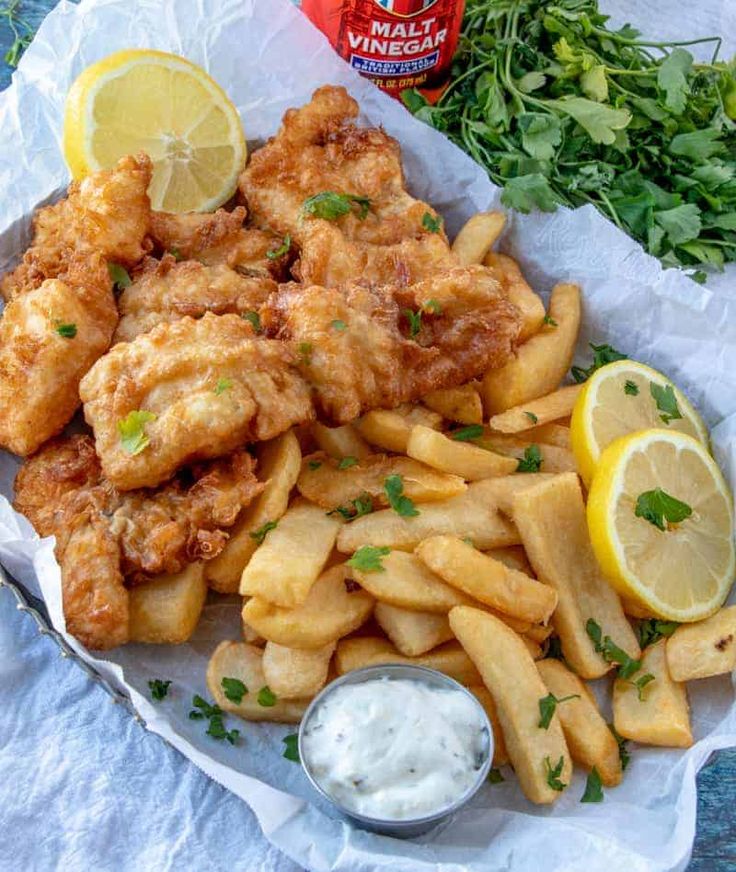 fried chicken and french fries with lemon wedges on the side