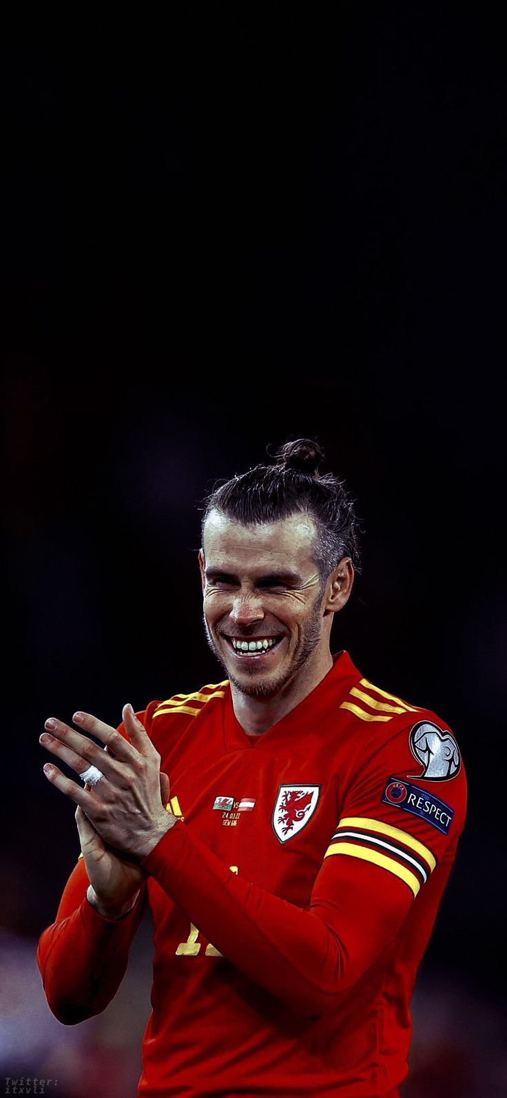 a soccer player with his hands together and smiling at the camera while wearing a red uniform