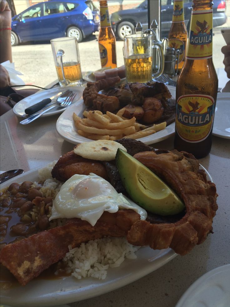 two plates filled with food next to bottles of beer and glasses on a table in front of them