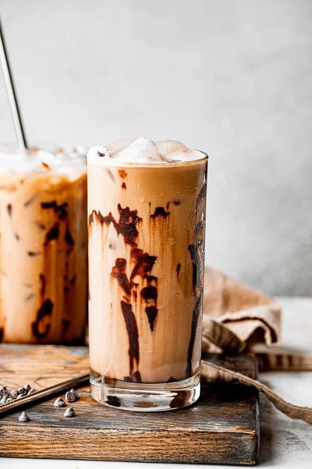 two glasses filled with iced coffee sitting on top of a wooden table