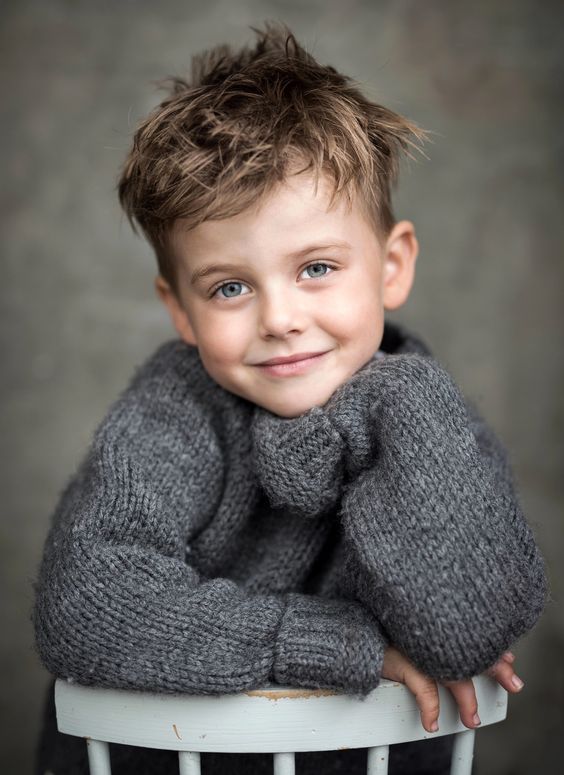 a young boy sitting on top of a white chair