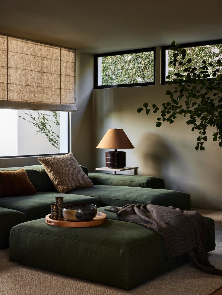 a living room with green couches and pillows on the floor next to a window