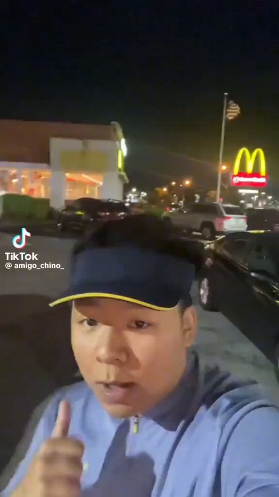 a man wearing a hat gives the thumbs up sign in front of a mcdonald's