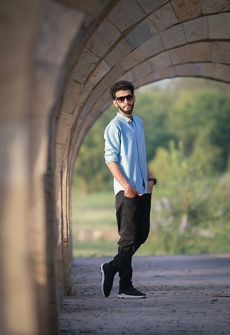 a man standing in the middle of a tunnel with his hands in his pockets and wearing sunglasses