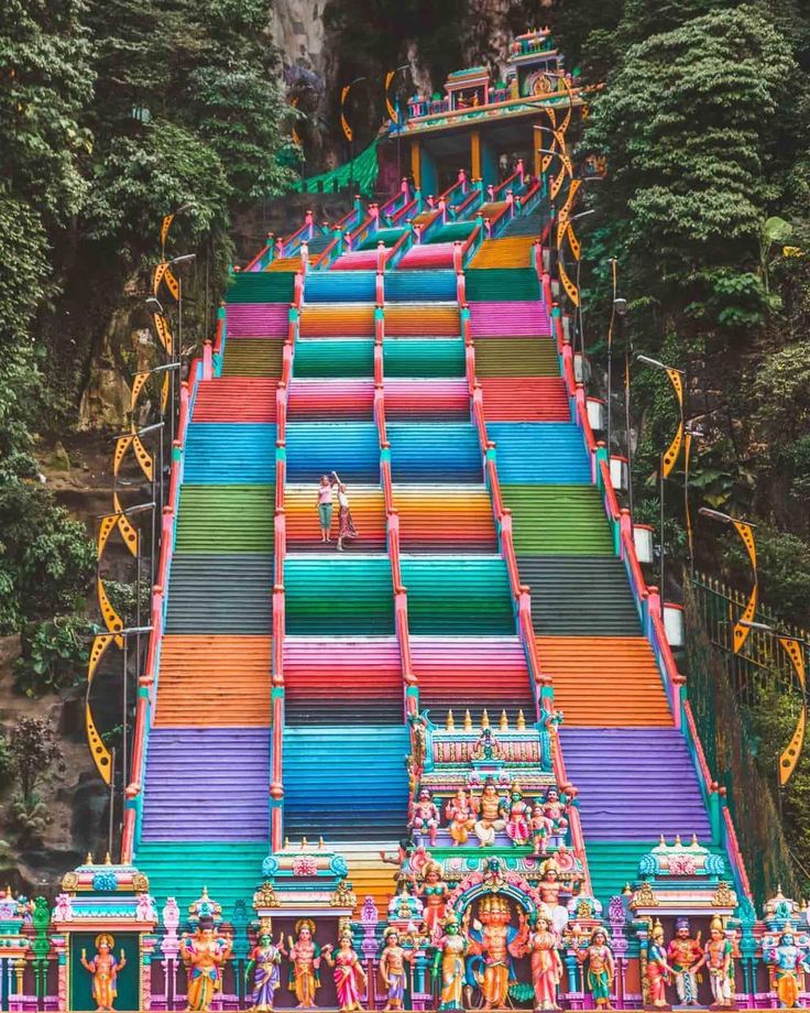 an elaborately painted slide in the middle of a jungle with lots of people on it