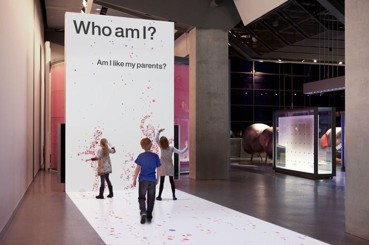 two children are standing in front of a sign that says who am? and another child is looking at it