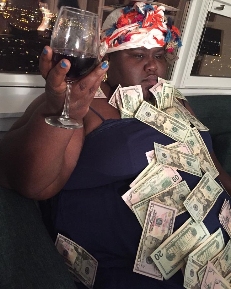 a woman sitting on a couch holding a glass of wine and money in her hands