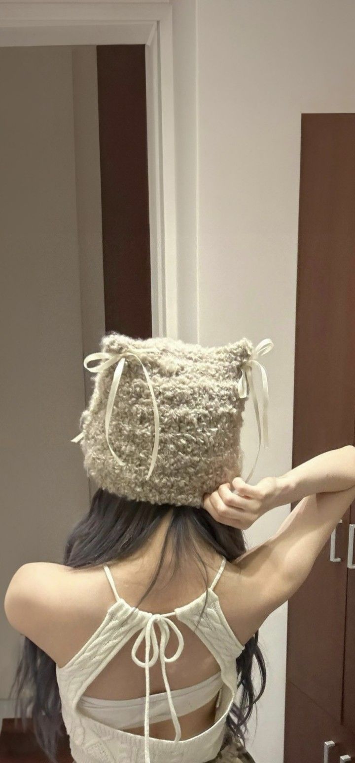 a woman with her back to the camera wearing a knitted hat on top of her head