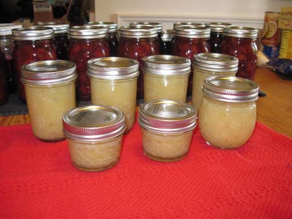 many jars filled with food sitting on a red table cloth next to some other jars