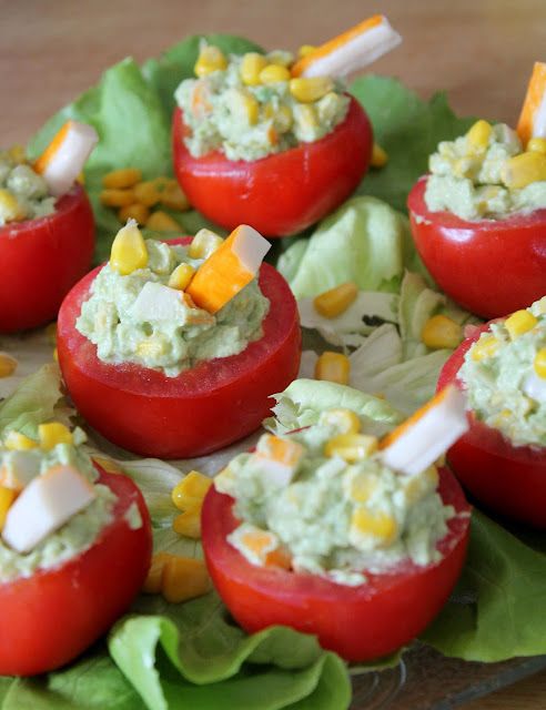 small stuffed tomatoes are topped with corn and mayonnaise on lettuce leaves