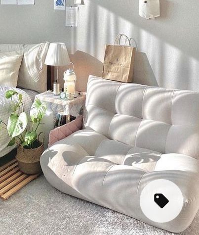 a living room filled with white furniture and lots of pillows on top of the floor