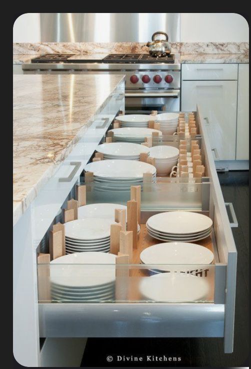 an open drawer in the middle of a kitchen with plates and bowls on it's side