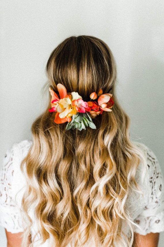 a woman with long blonde hair and flowers in her hair, wearing a white top