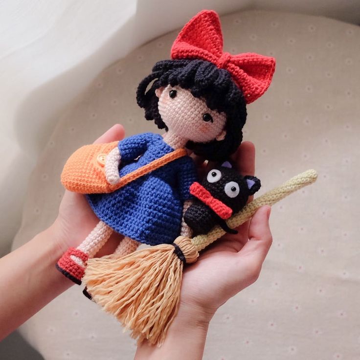 a hand holding a crocheted doll and cat