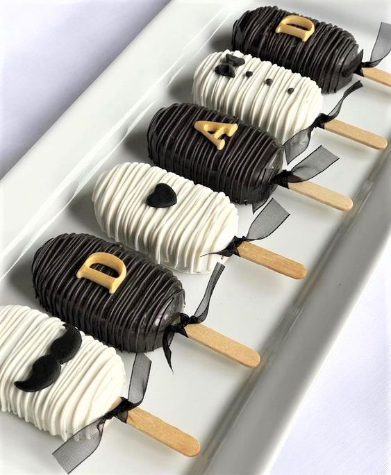 four desserts are arranged in the shape of panda faces on sticks with black and white icing