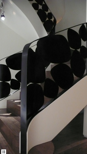 a spiral staircase with black and white decorations on the bottom handrail in a modern building