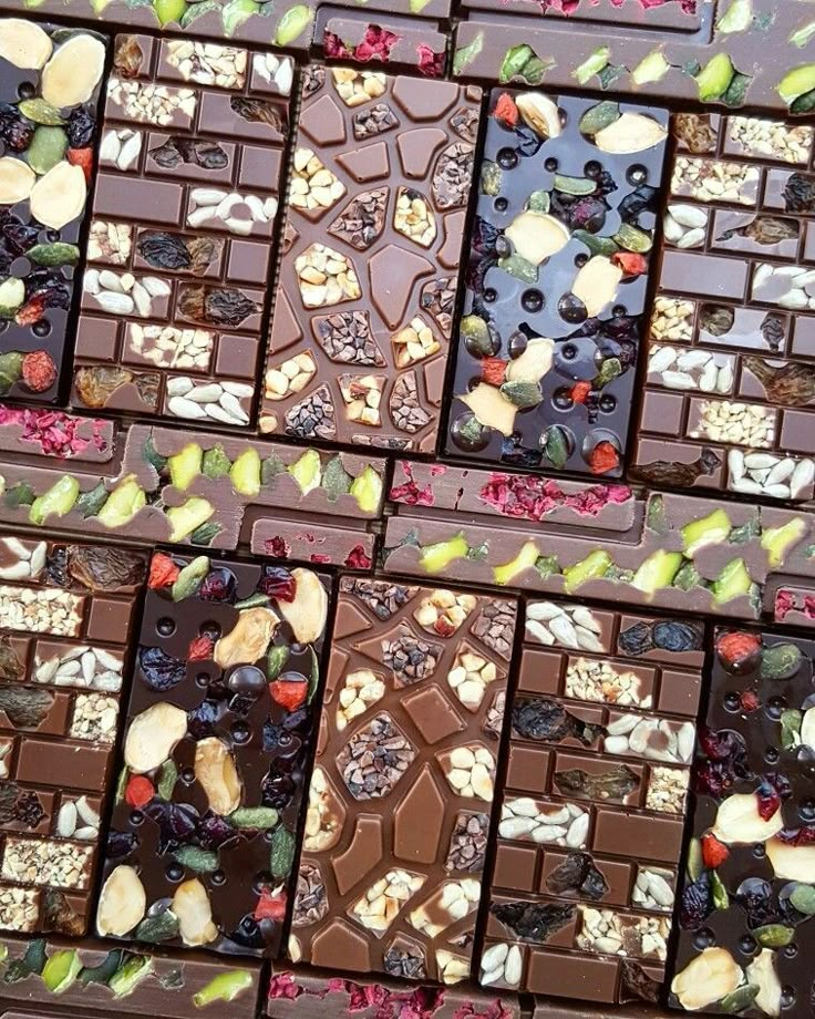 several pieces of chocolate with fruit and nuts on top, arranged in rows to look like mosaics