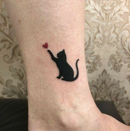 a black cat with a red heart tattoo on the ankle