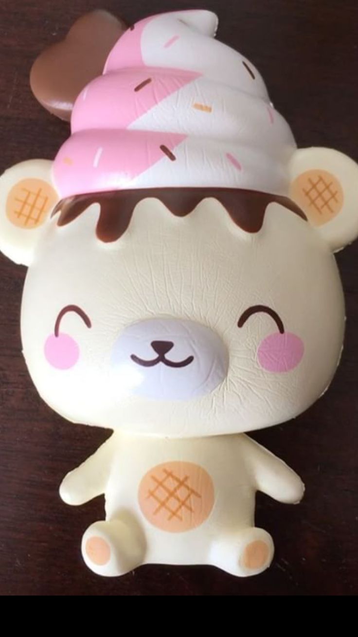 a white bear with pink and brown ice cream on it's head sitting on a table