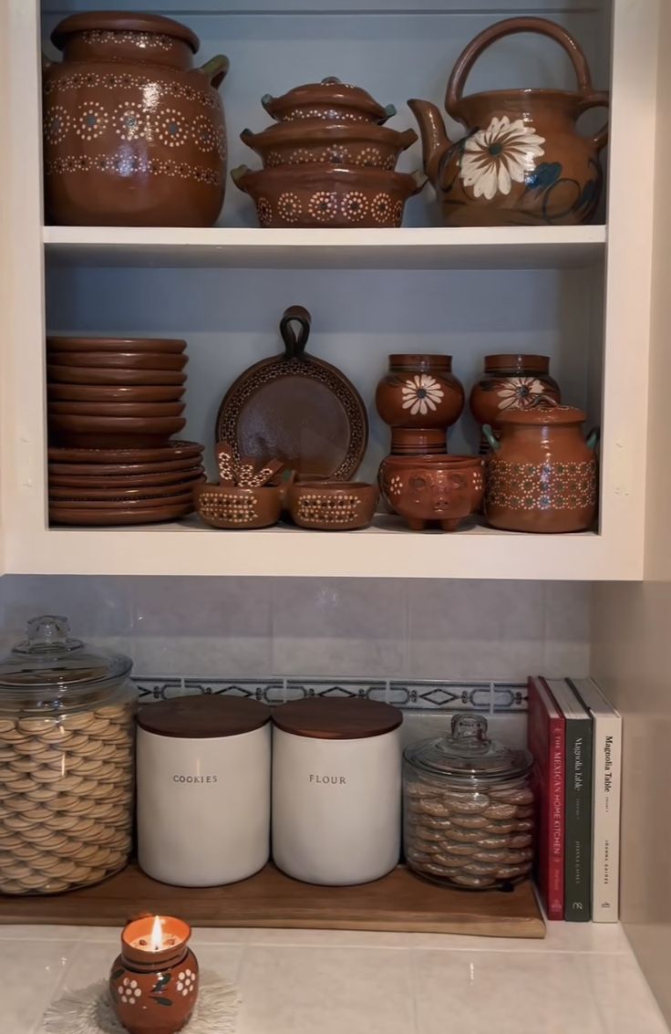 the shelves in the kitchen are filled with pots and pans, dishes, and candles