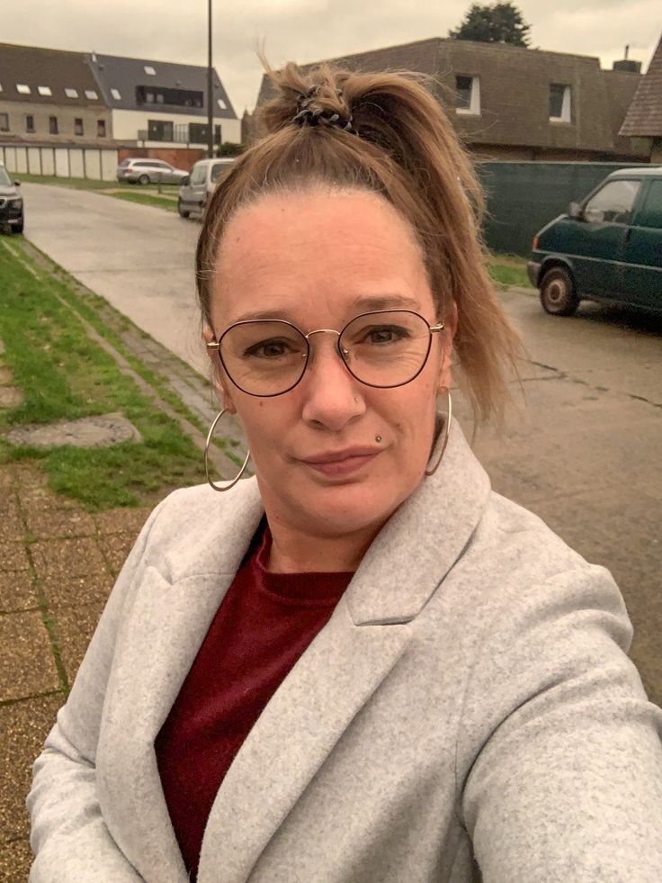 a woman with glasses is standing in the street