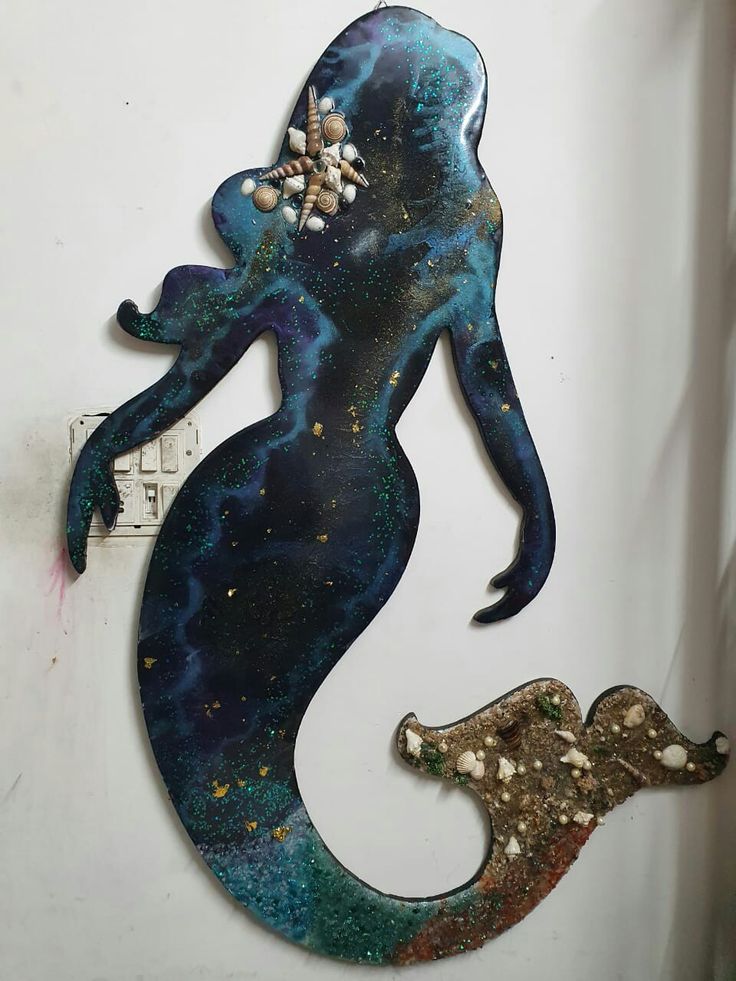 the metal mermaid is hanging on the wall