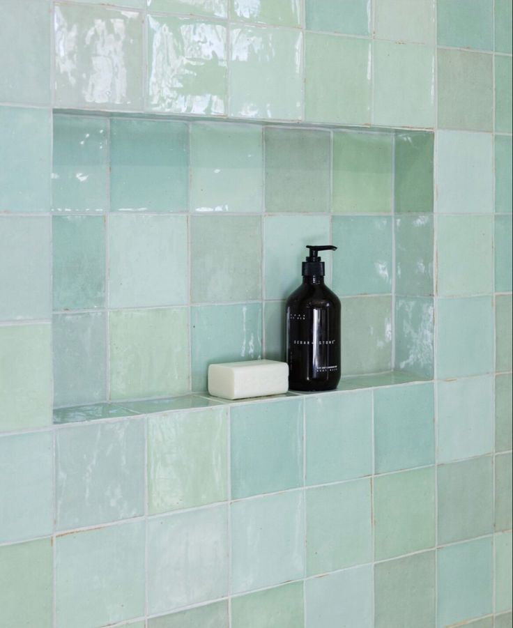 a black bottle sitting on top of a shelf next to a soap dispenser