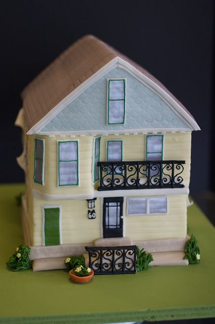 a cake shaped like a house with green shutters and balconies on the balcony