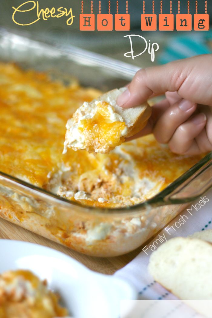 a hand holding a piece of bread over a casserole dish with cheese on top