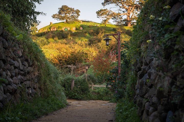 an alley way with stone walls and green hills in the backgrouds, surrounded by greenery