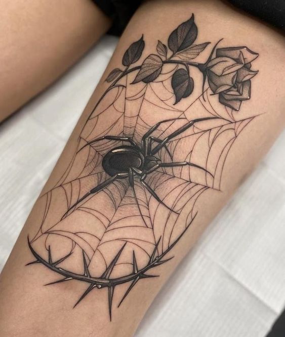 a spider web tattoo on the thigh with roses and leaves in it's center