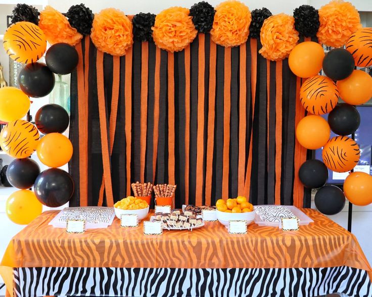 an orange and black dessert table with balloons