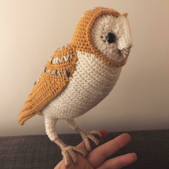 a small knitted owl sitting on top of a persons hand