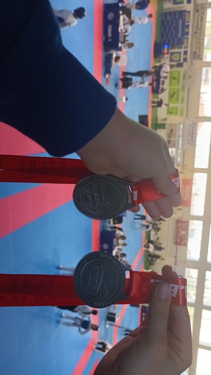 a person is holding two coin in front of a boxing ring with other people on it