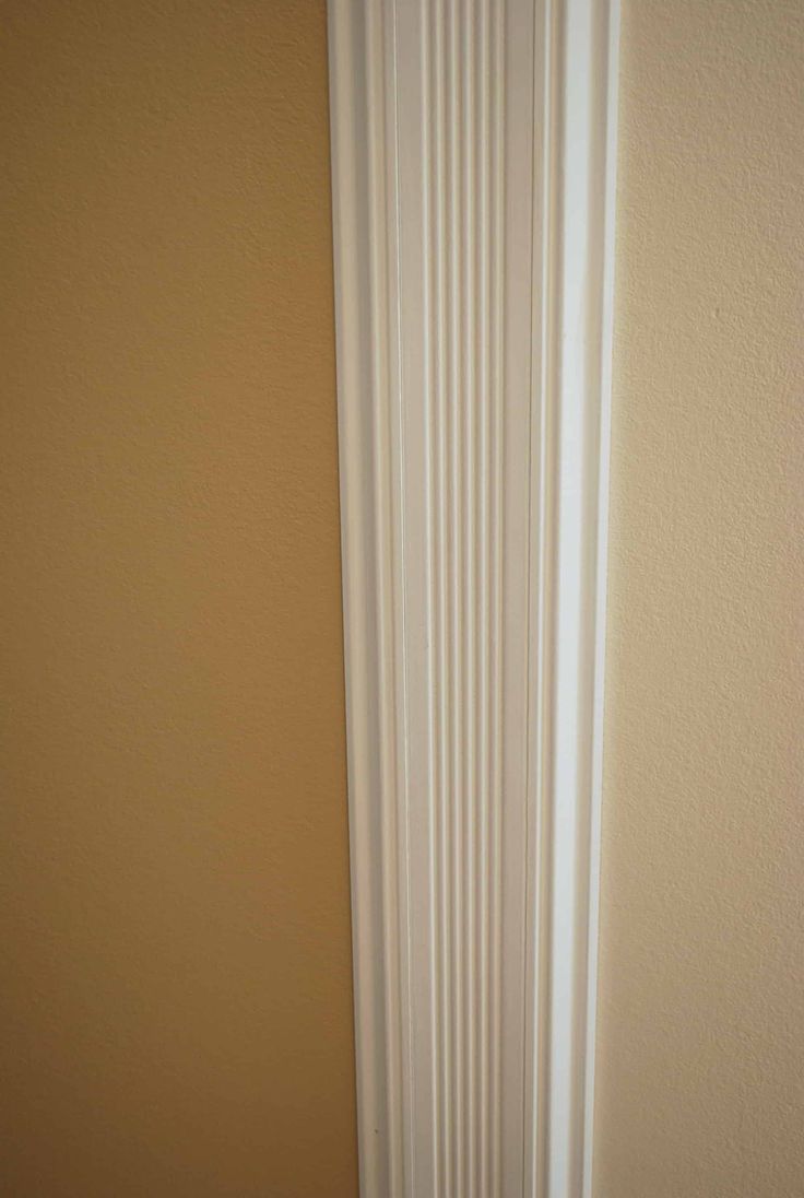 the corner of a room with a white radiator and tan walls in it