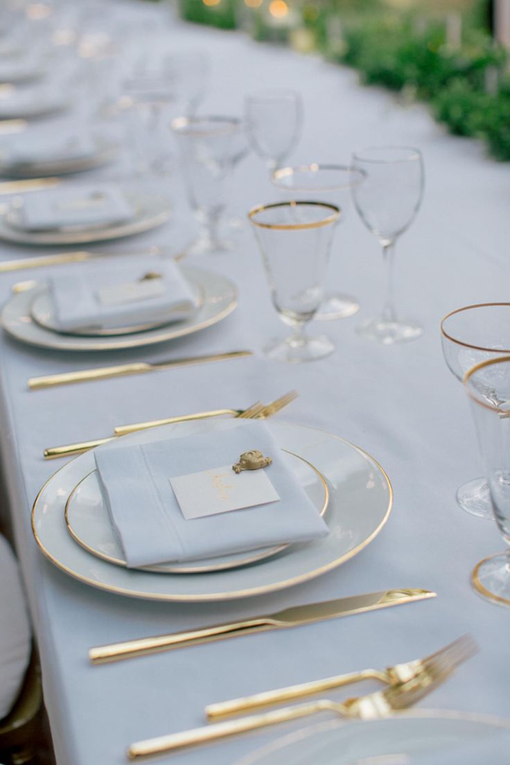 the table is set with white and gold place settings