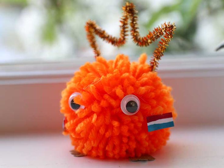 an orange stuffed animal with googly eyes and a flag on it's head