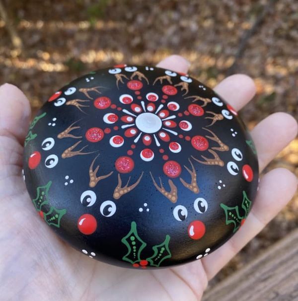 a hand holding a painted rock with christmas decorations on it