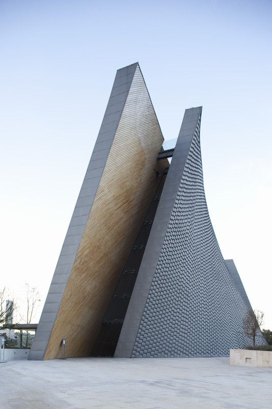 the side of a building that is made out of metal and wood with a triangular design