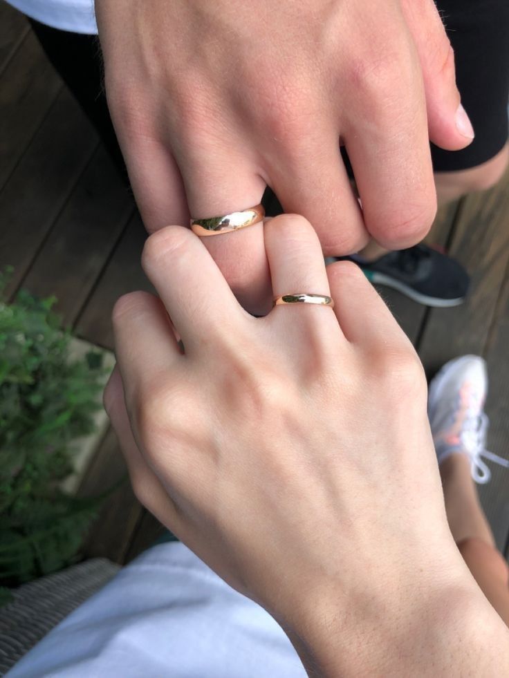 two people with wedding rings on their fingers, one holding the other's hand