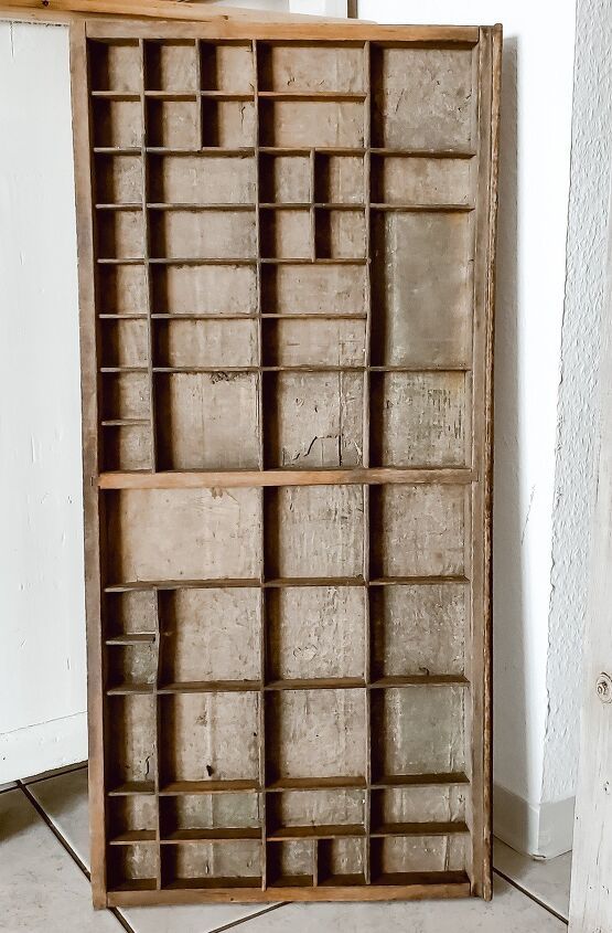 an old wooden box with many compartments on the bottom and sides, in front of a white wall