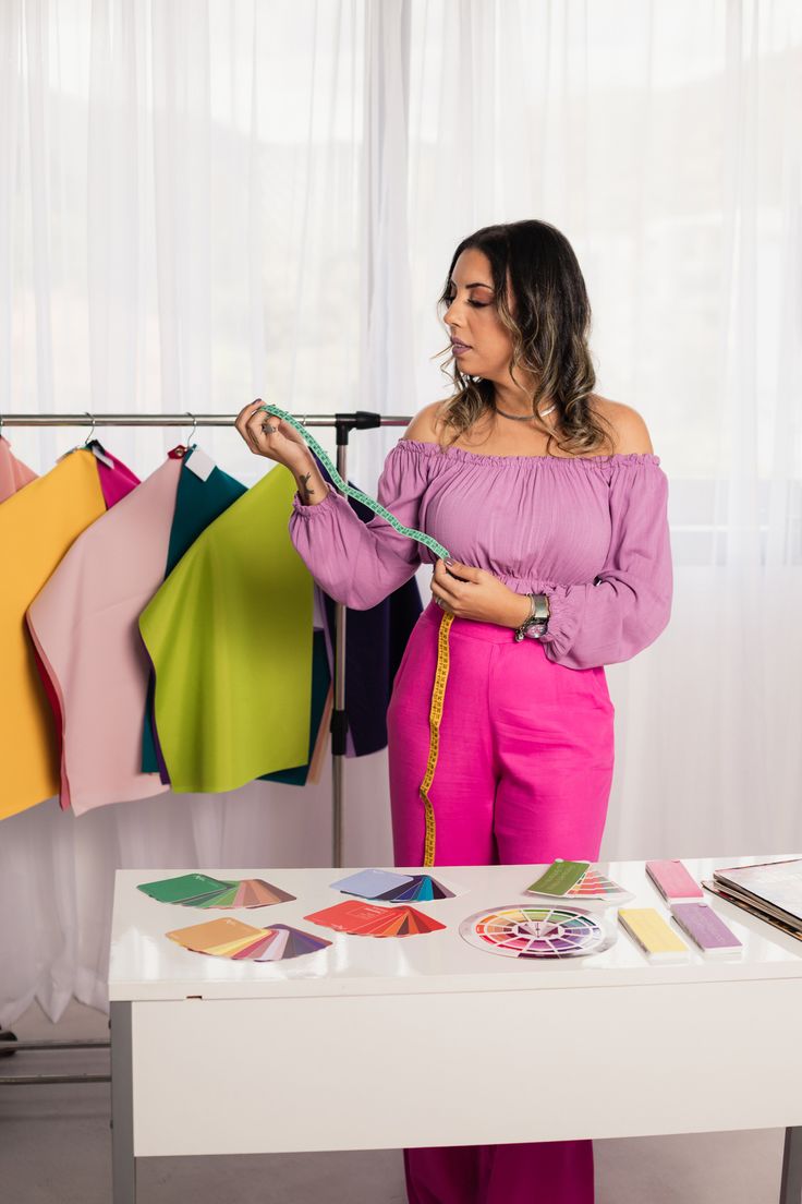 a woman standing in front of a table with clothes hanging on the rack and other items