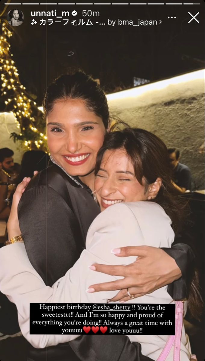 two women hugging each other in front of a christmas tree with lights on the background