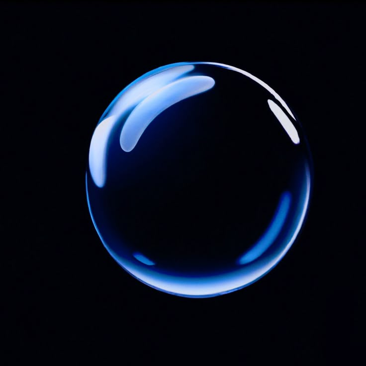 a blue bubble floating in the air on a black background with light reflecting off it's surface