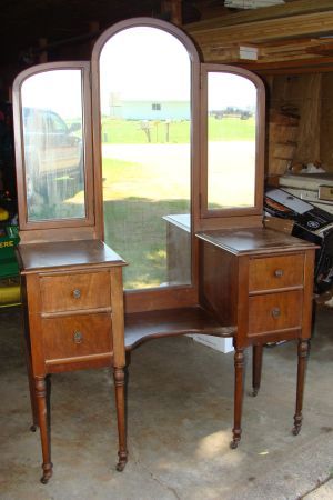 an antique desk and chair in a garage with two windows on one side, and a mirror on the other