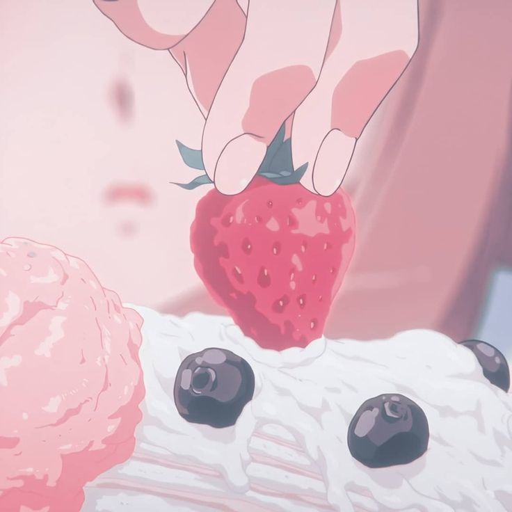 a person holding a strawberry on top of a piece of cake