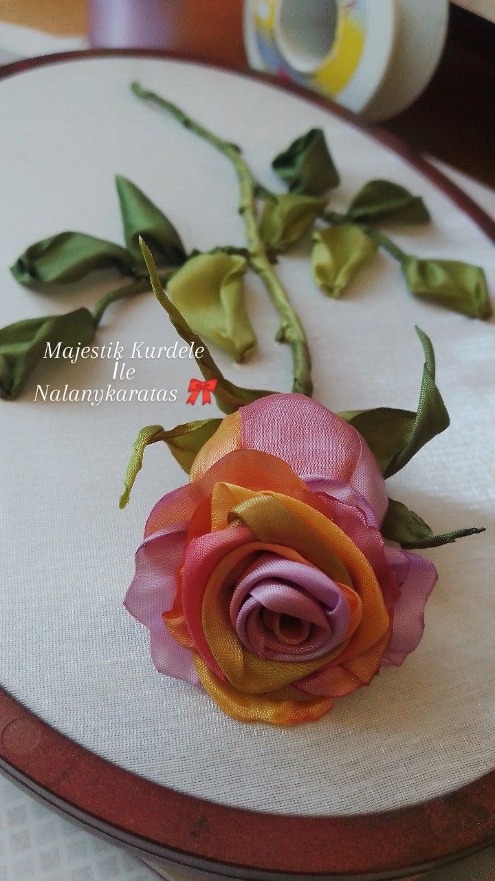 a close up of a flower on a table with some thread and scissors in the background