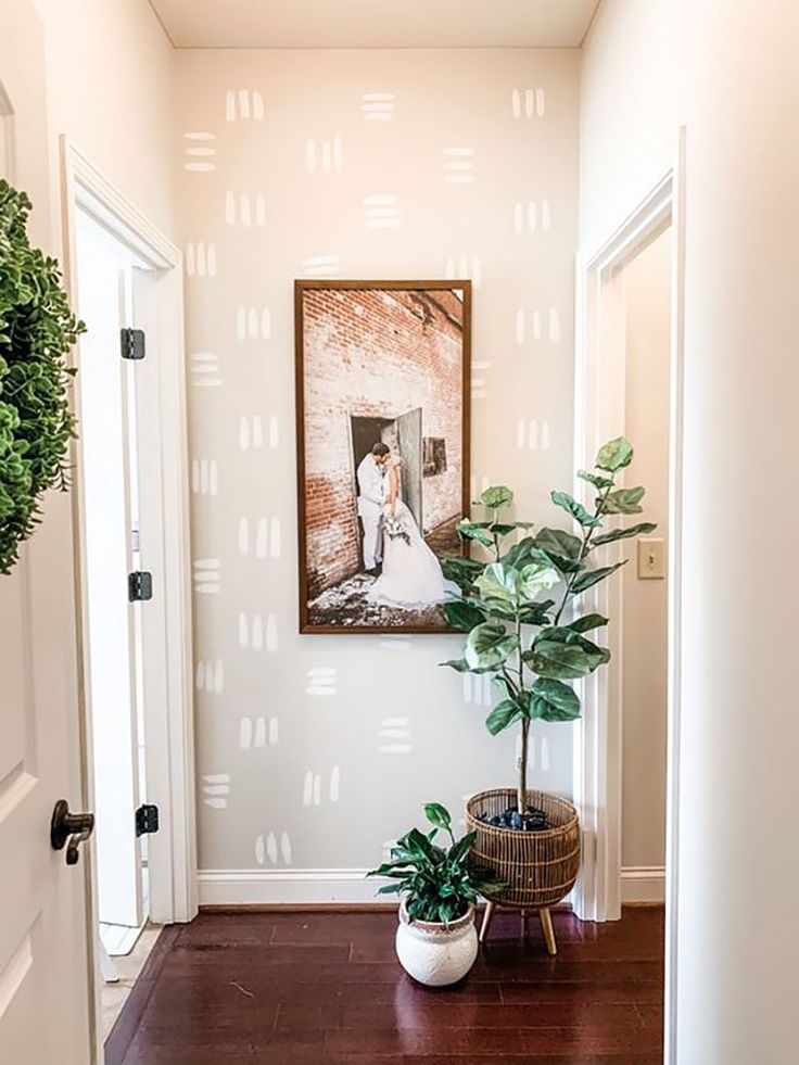 there is a potted plant sitting on the floor in front of a photo hanging on the wall