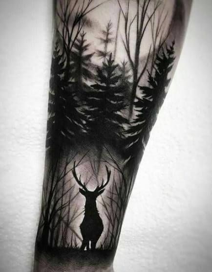 a man's arm with a black and white tattoo of a deer in the woods