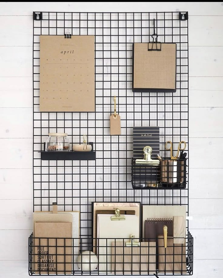 a black wire wall mounted to the side of a white wall filled with office supplies